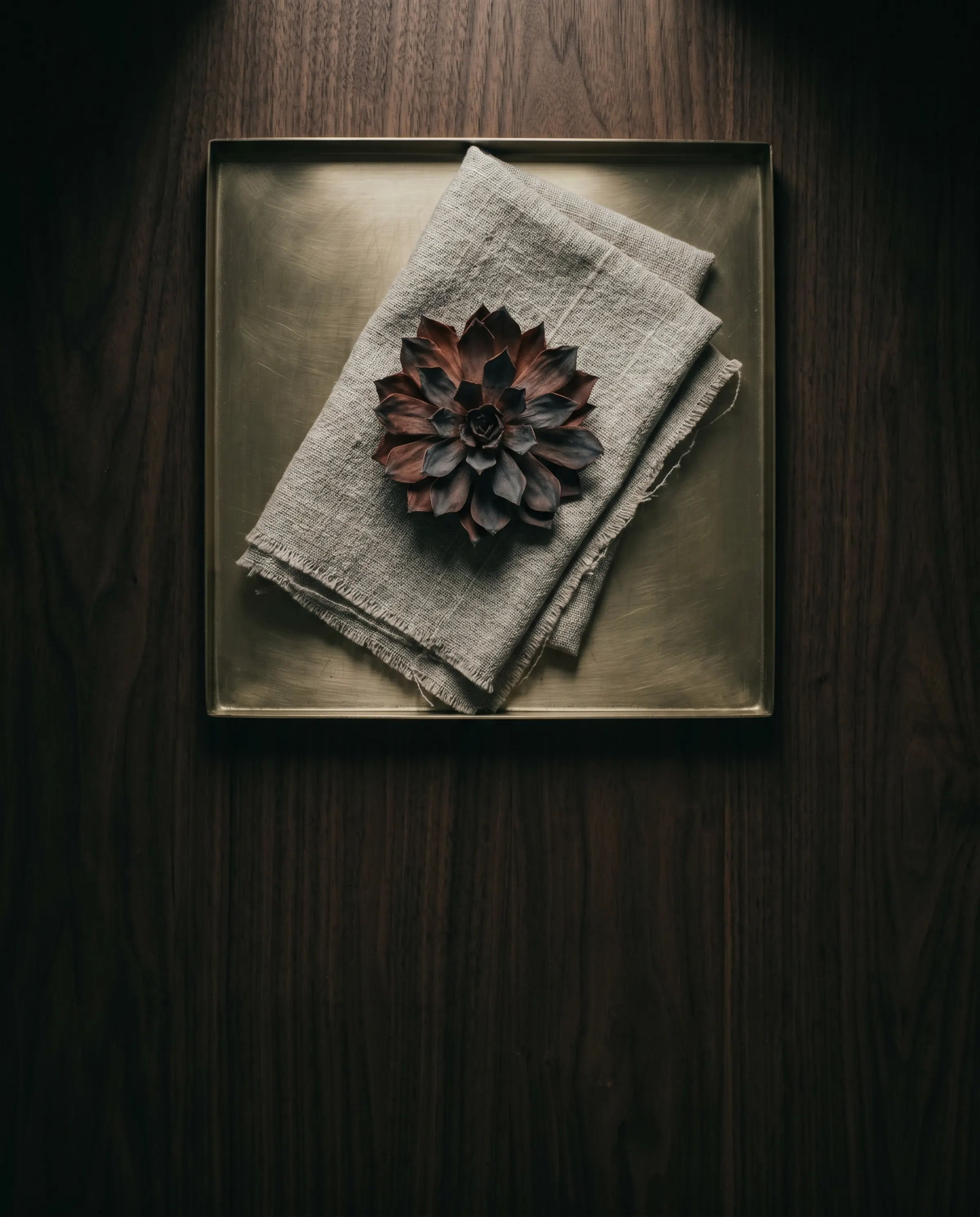 Brass tray, folded linen, single dried bloom